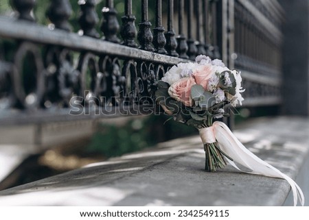 wedding bouquet tilted to metal fence outdoor, wedding photosession concept Royalty-Free Stock Photo #2342549115