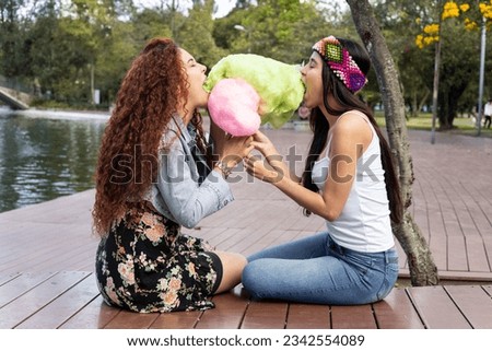 romantic date of a young couple of women, enjoying the day in a park and eating an exquisite cotton candy, love relationship and good times, people