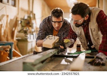 Two carpenters working together in a woodworking shop Royalty-Free Stock Photo #2342557821
