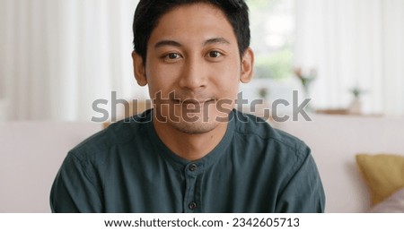 Close-up adult male Gen Z asia people relax look at webcam camera toothy smile sit at home sofa couch. New house owner young latin man guy happy joy cheerful face in urban modern health care lifestyle Royalty-Free Stock Photo #2342605713