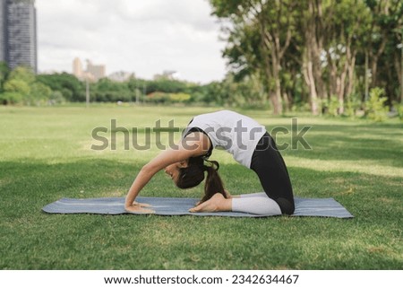 young woman have a beautiful body, Playing yoga in an elegant posture, in the green park, concept to people's recreation and health care concept.blurred background