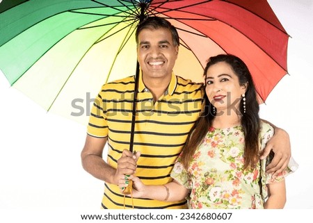indian couple holding colorful umbrella on white background.