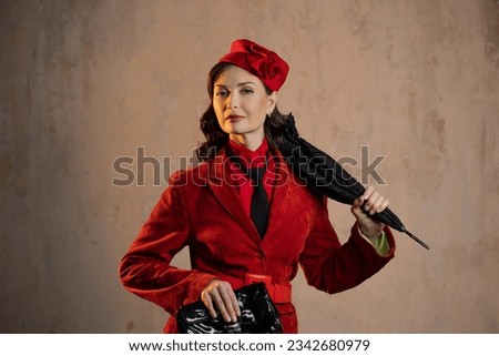 A stylish lady in a red old-fashioned suit with a hat and a lace umbrella Royalty-Free Stock Photo #2342680979