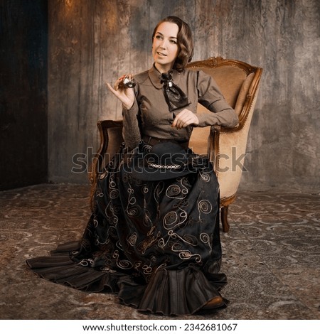 A stylish lady in an elegant Victorian-style suit, sitting in an armchair. costume with steampunk elements, Royalty-Free Stock Photo #2342681067