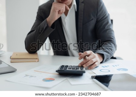 Tired exhausted asian man using a calculator sitting at desk, overworked, stressed man,