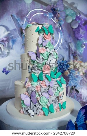 Beautiful multi-tiered birthday cake decorated with flowers from top to bottom and butterflies sitting on them