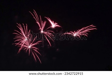 a photography of a bunch of fireworks in the night sky, fireworks are lit up in the dark sky with red lights.