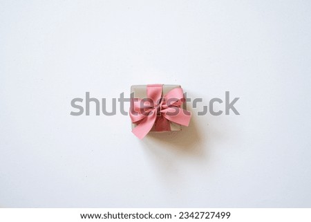 Gray gift box and coral pink ribbon isolated on white background. top view, copy space