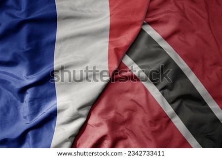 big waving realistic national colorful flag of france and national flag of trinidad and tobago . macro