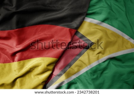 big waving realistic national colorful flag of germany and national flag of guyana . macro