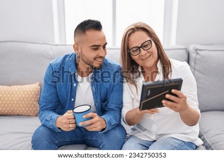 Man and woman mother and son drinking coffee looking photo at home