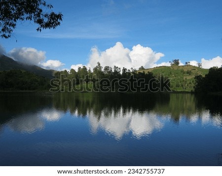 fresh and calm water surrounded by green trees and clear sky at Telagawarna Dieng. The photo was taken by Willem Tasiam, a marathon climber
