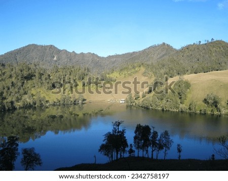 calm water surrounded by green trees in Ranukumbolo Semeru, East Java. The photo was taken by Willem Tasiam, a marathon climber