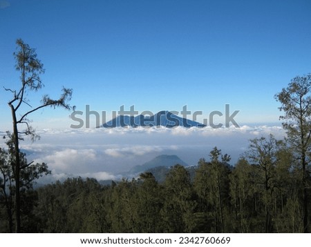 view of Mount Arjuna, Welirang seen from Mount Butak, decorated with green trees, white clouds and bright sky. The photo was taken by Willem Tasiam, a marathon climber