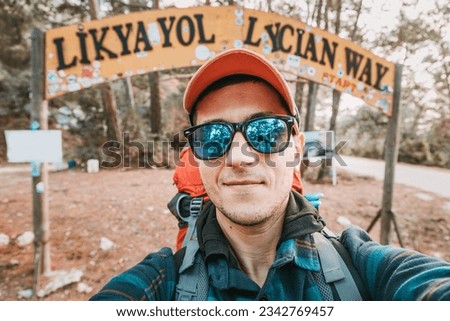Happy hiker man with trekking backpack taking selfie photo at a starting point of Lycian Way trail in Oludeniz, Fethiye. Travel and adventure in Turkey