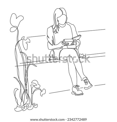 Woman reading book. Sitting on park bench close to abstract flowers bed.