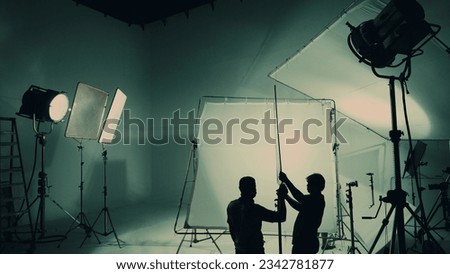 Silhouette of video production behind the scenes or B roll or making of TV commercial movie that film crew team lightman and cameraman working together with director in big studio with pro equipments Royalty-Free Stock Photo #2342781877