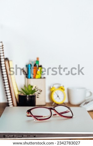 the closed notebook was placed on the desk in the room, women's glasses put away, vertical photo, copy space