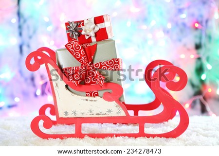 Wooden toy sledge with Christmas gifts  on shiny background