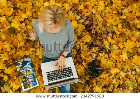 woman with laptop and photo book in autumn park