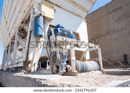 Concrete production technology. Electric motor with belt drive to reducer, to drive the conveyor belt for transporting gravel and sand in a concrete plant. Royalty-Free Stock Photo #2342796107