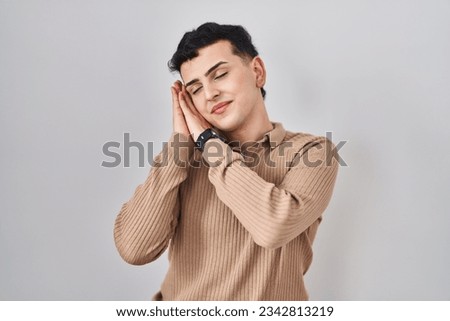 Non binary person standing over isolated background sleeping tired dreaming and posing with hands together while smiling with closed eyes. 