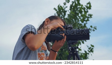                                The girl puts the camera on a tripod, she is preparing to take a picture