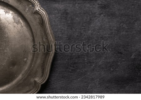 Close up of vintage pewter plate on black chalkboard background. Flat lay. Top view. Food concept. Dark mood food photography.