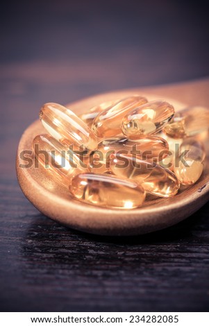 Cod liver oil omega 3 gel capsules isolated on wooden background 
