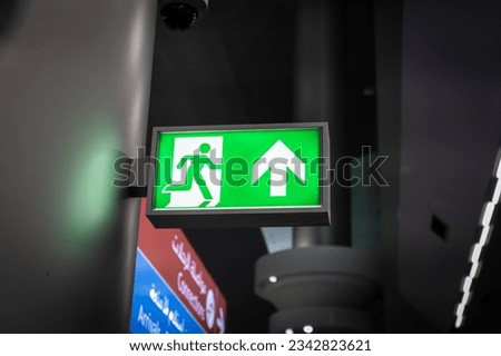 A glowing green exit sign illuminated against a black background, indicating the path to safety