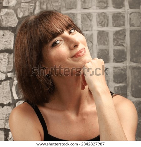 Beautiful woman smiling for the camera, taking a selfie, sitting in the cafeteria. forelock, brown long hair, freckled girl. stone wall background, green eyes, white skin, turkish model. Royalty-Free Stock Photo #2342827987