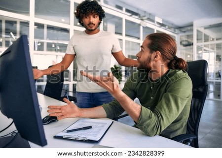 Two multiracial male freelancers discussing work and business in a modern coworking office while sitting at a computer. Colleagues argue, badly done job. Royalty-Free Stock Photo #2342828399