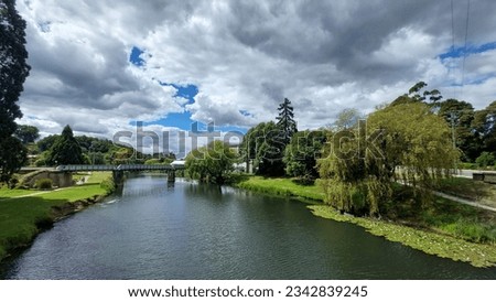 A scenic river in Deloraine, Tasmania surrounded by lush green foliage in a park setting Royalty-Free Stock Photo #2342839245
