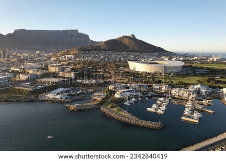 A drone shot of white ships near wooden docks on the green-covered coast of a sea in Cape Town