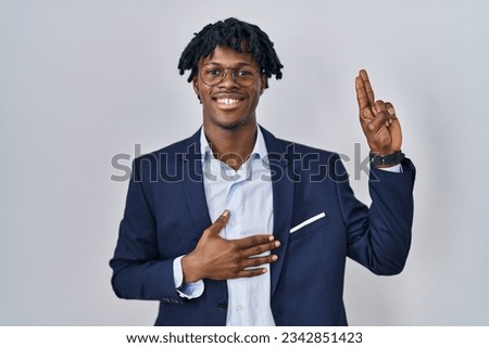 Young african man with dreadlocks wearing business jacket over white background smiling swearing with hand on chest and fingers up, making a loyalty promise oath  Royalty-Free Stock Photo #2342851423