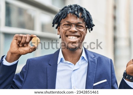 Young african man with dreadlocks holding virtual currency bitcoin screaming proud, celebrating victory and success very excited with raised arm  Royalty-Free Stock Photo #2342851461