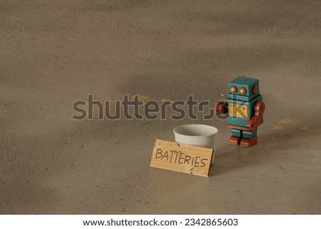 A stray toy robot in the street begging for batteries - concept of need for power