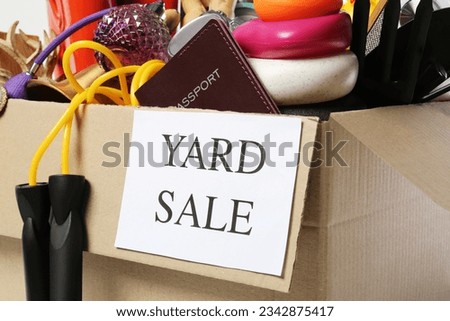 Sign Yard Sale written on box with different stuff, closeup