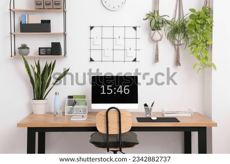 Cozy workplace with computer, modern furniture and houseplants at home Royalty-Free Stock Photo #2342882737