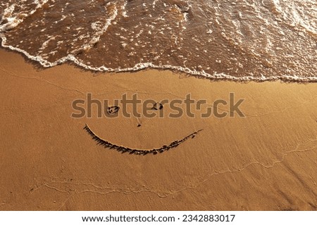 emoticon happy smile face painted on jetted beach sand by sea