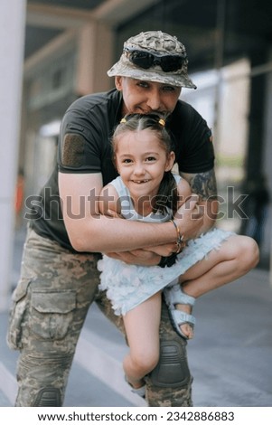 Little Ukrainian girl meets her father from the war during his vacation and cheerful plays with him. War in Ukraine. Russian military invasion in Ukraine. War and children.