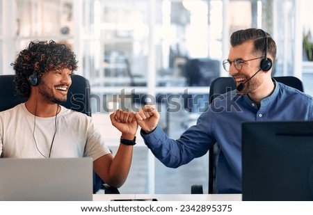 Call center employee accompanied by his team. Focused support operator at work. Young employee working with headset and laptop. Royalty-Free Stock Photo #2342895375