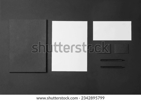 Corporate stationery set mockup. Presentation folder, letterheads and two business cards at black textured paper background.  Royalty-Free Stock Photo #2342895799