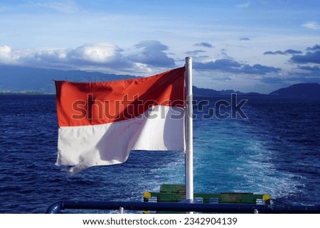 The Indonesian flag waving proudly atop the deck of a Ferry ship from Banda Aceh to Sabang against the blue sky. Royalty-Free Stock Photo #2342904139
