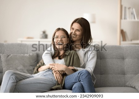 Happy mom and teenager daughter home casual portrait. Mother and teen girl resting on home sofa, hugging, talking with trust, having fun, laughing, enjoying bonding, friendship, relationships Royalty-Free Stock Photo #2342909093