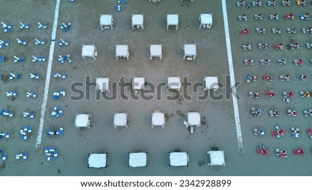 Top down aerial view to beach umbrellas in the morning after the rain, wet sand, raining morning at the beach or end of summer season concept. 