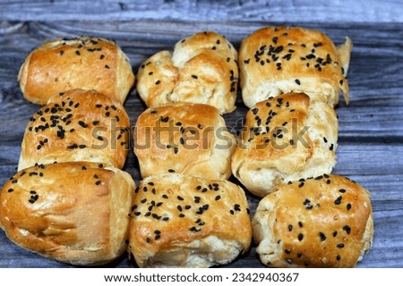 mini salty baked pastries topped with black seeds Baraka seed and stuffed with slices of alive, traditional bakeries used as snacks between the meals isolated on wooden background, selective focus Royalty-Free Stock Photo #2342940367