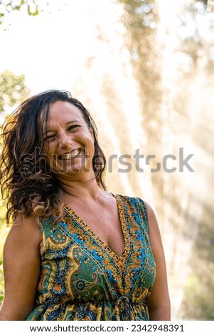 portrait of beautiful middle aged woman in front of a fountain in a park at sunset