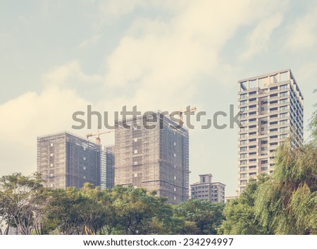 Looking Up at High Rise Buildings Under Construction as part of Urban Skyline with Tree Tops