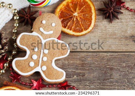 Homemade christmas painted gingerbreads (gingerbread man and red boot) on the wooden background with Christmas decorations, cones and candied orange. Selective focus and place for text. Toned